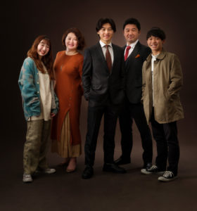 ブラウンのスクリーンで家族５人立ち全身