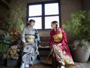 座った振袖を着た2人が見合って笑っている