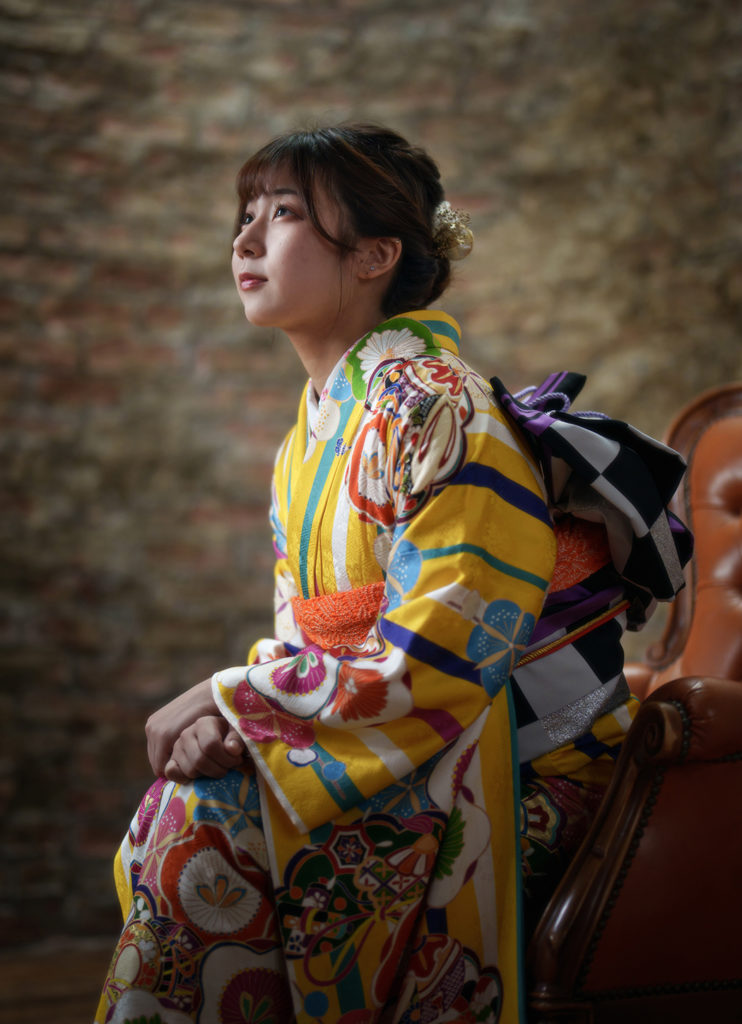 振袖を着て椅子に座り横向きの女性