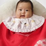 赤い着物を着て100日祝い写真